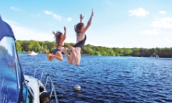 Two girls jumping off a boat into a lake in CT