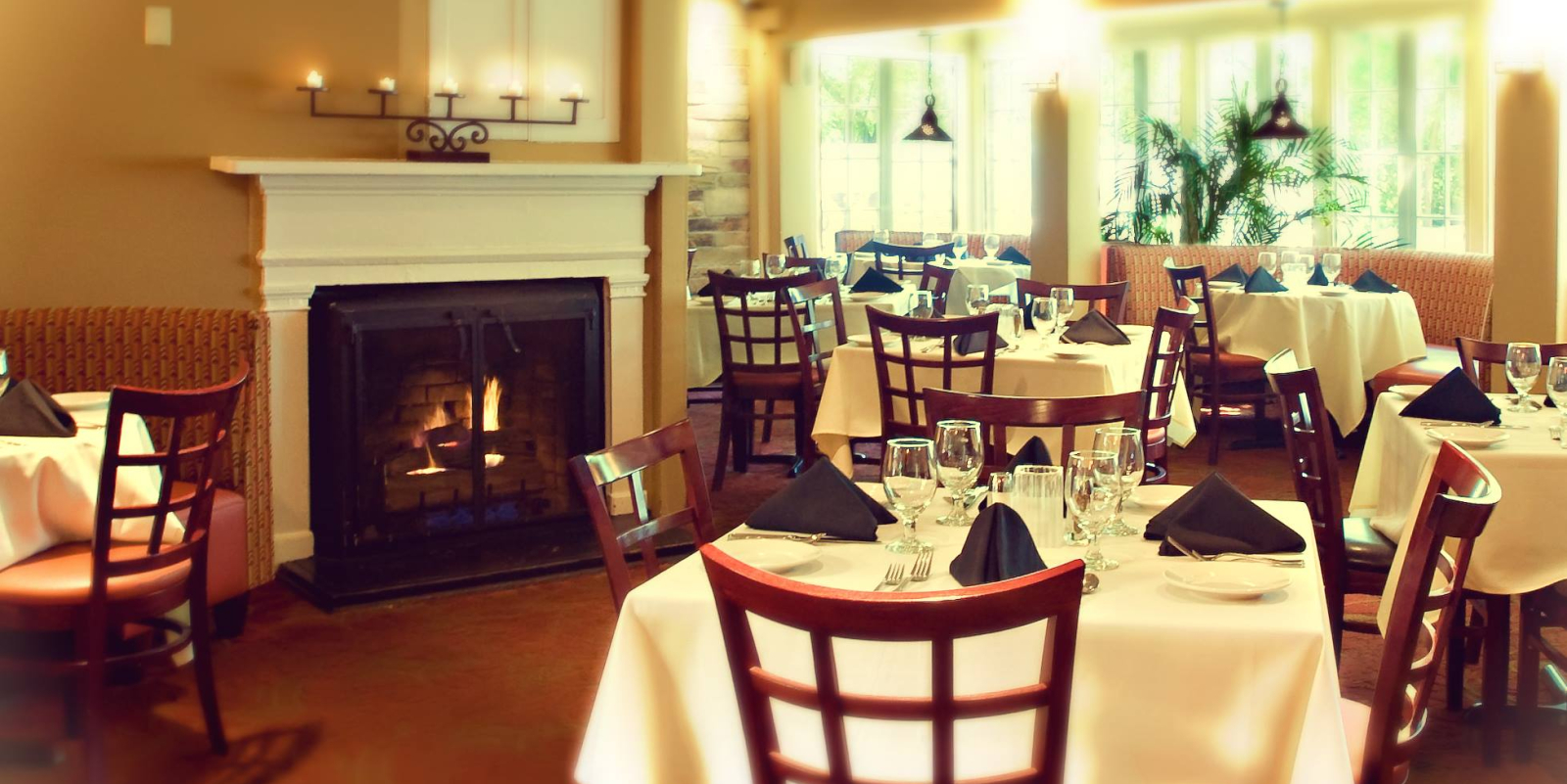 Cozy dining room with fireplace, set tables, and large windows