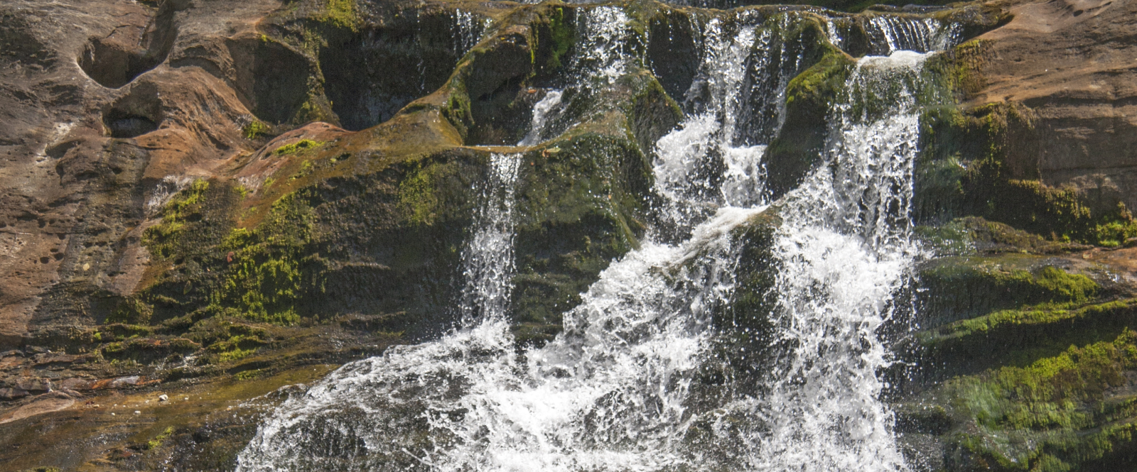 Multi-tiered waterfall flowing over mossy rocks and boulders