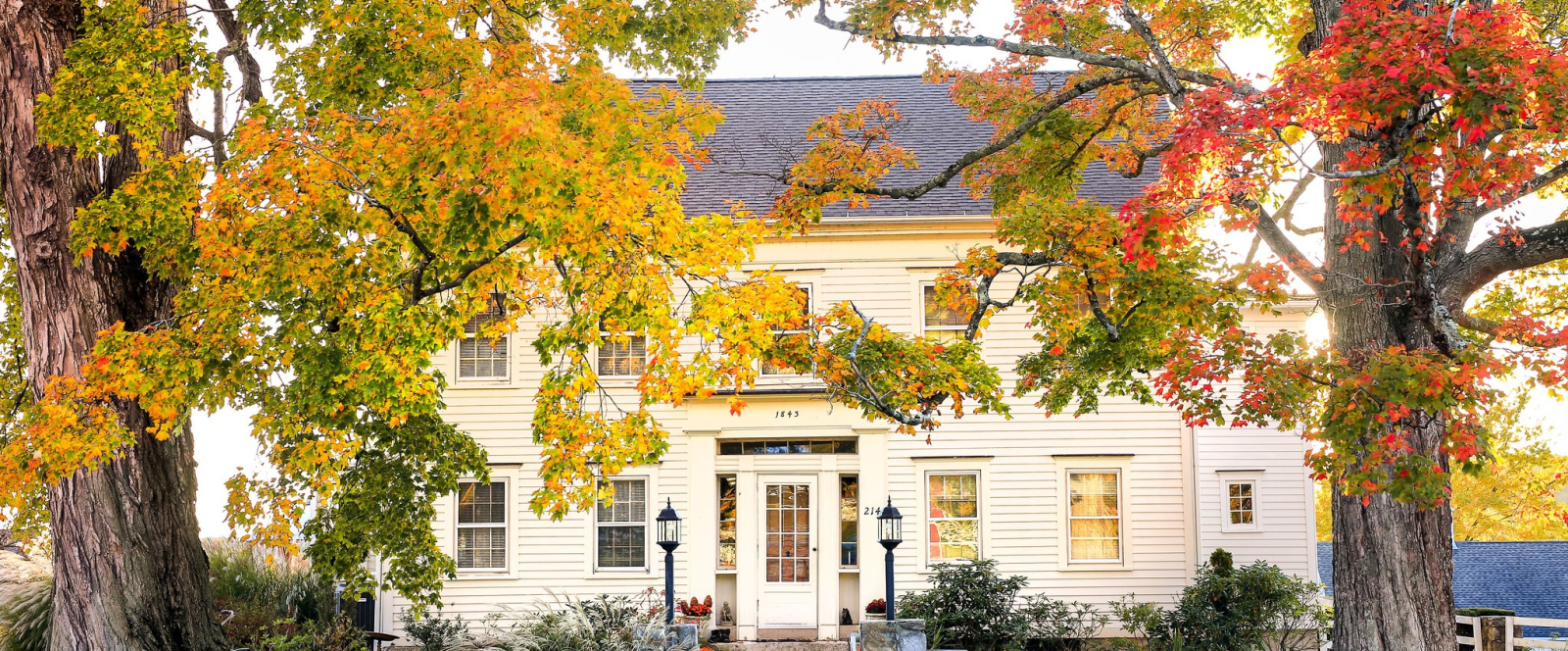 Historic white inn surrounded by autumn trees with colorful leaves