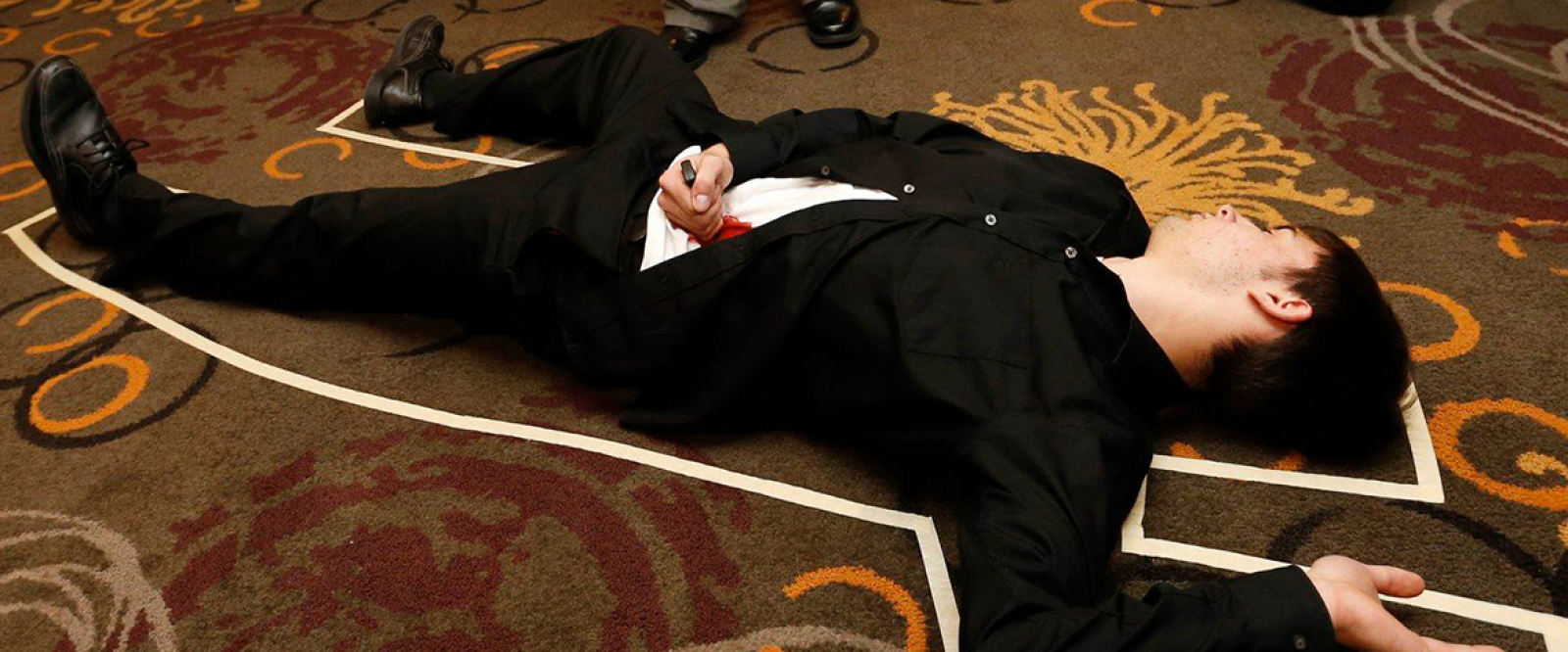 Man lying on floor in chalk outline resembling a crime scene