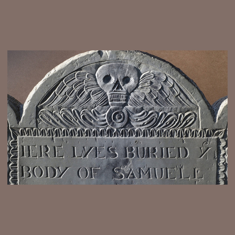 Old gravestone with winged skull carving and partial epitaph