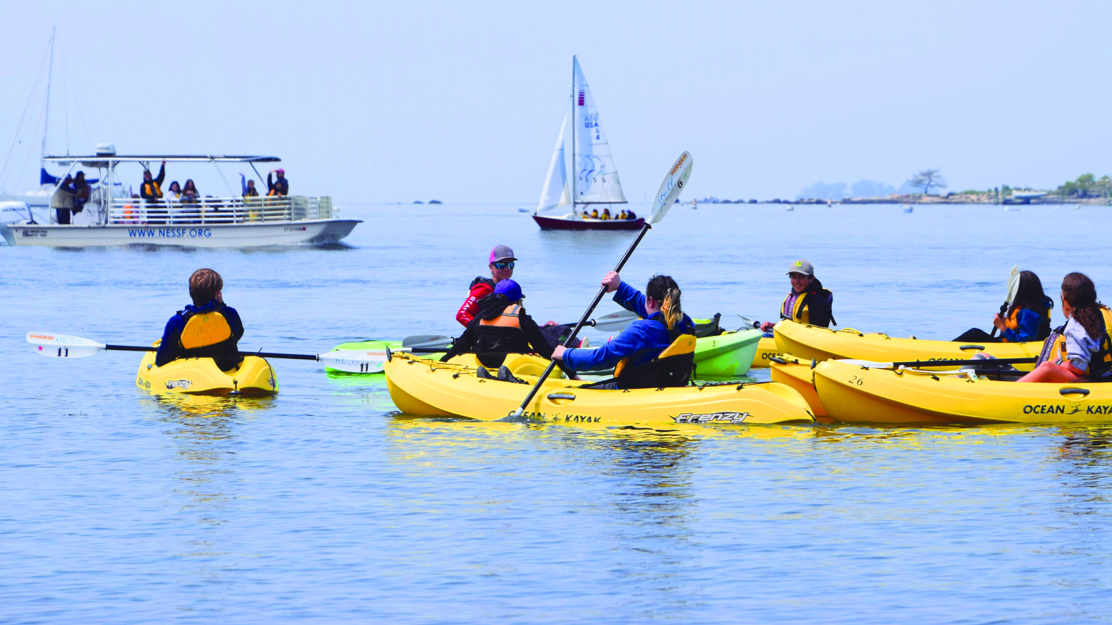 A school group experiences a rotation of three classes: kayaking, on-the-water water quality lab testing, and sailing
