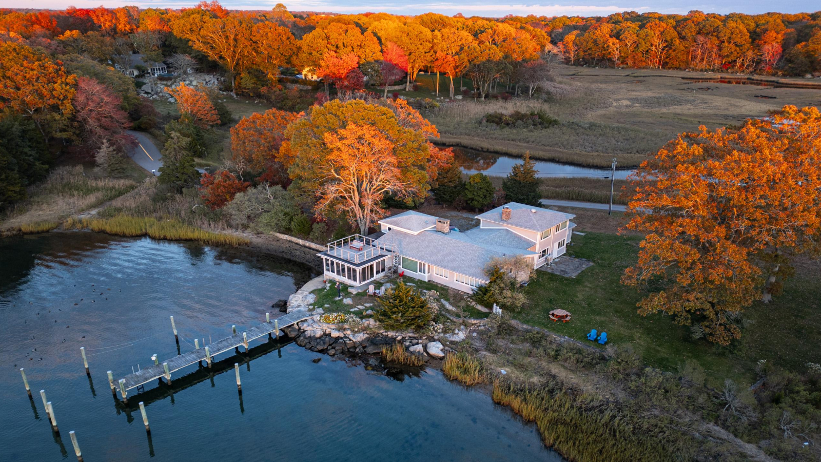 Aerial view of 26 Schoolhouse at the edge of the Mystic River, amid autumn marsh and trees