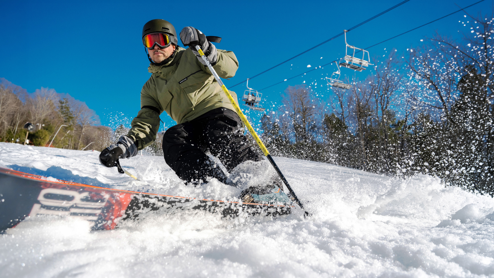 Skier carving on trail and creating snow spray