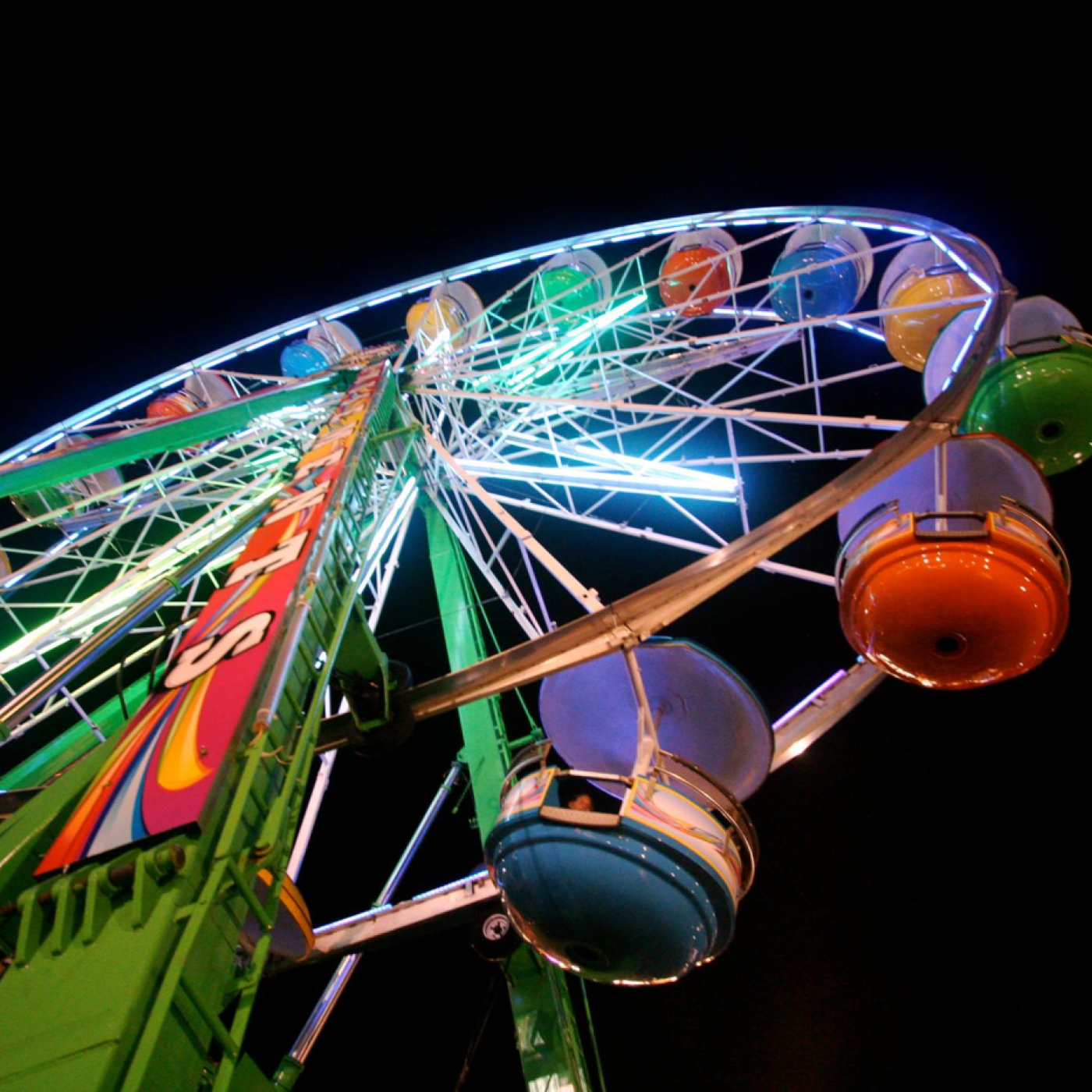 Colorful Ferris wheel lit up at night against black sky