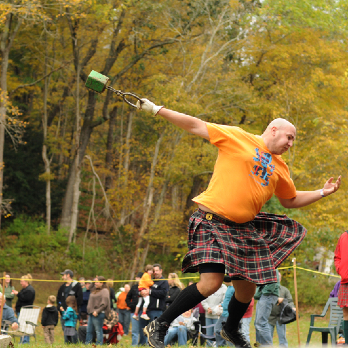 Man in kilt throwing hammer at Highland Games outdoors