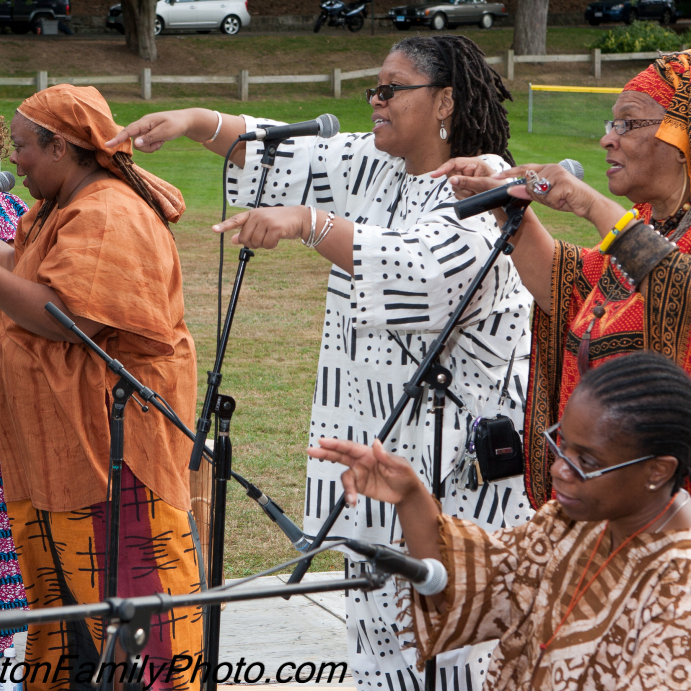Group of women in colorful traditional African clothing singing with microphones outdoors