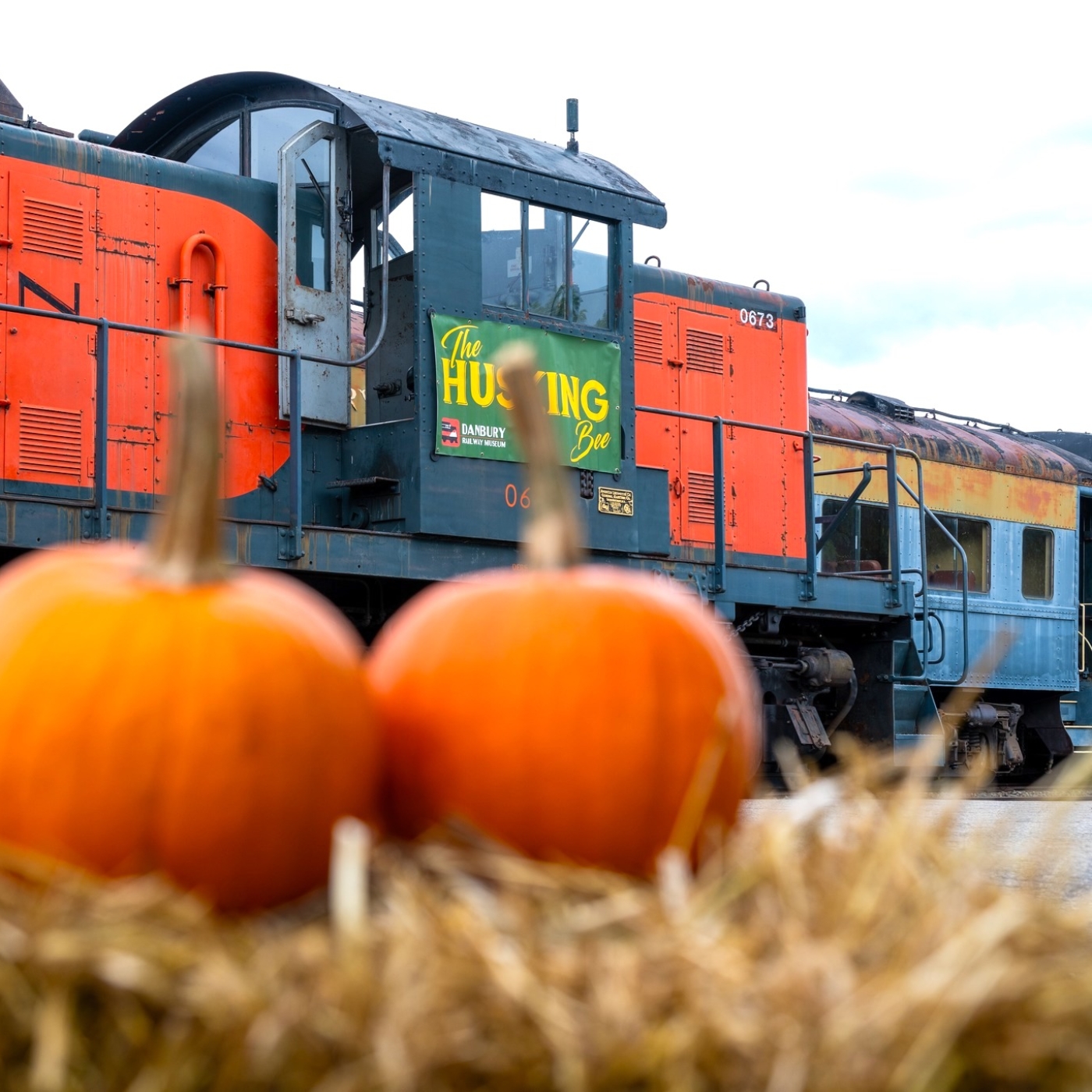 pumpkins on a hay bale in front of a train. 