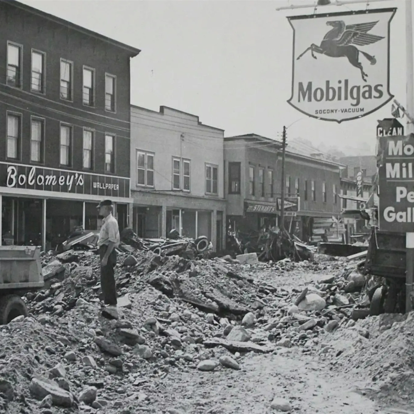 Historical photo of the town of winsted with rubble and deposits piled up in the streets following the flood of 1955.