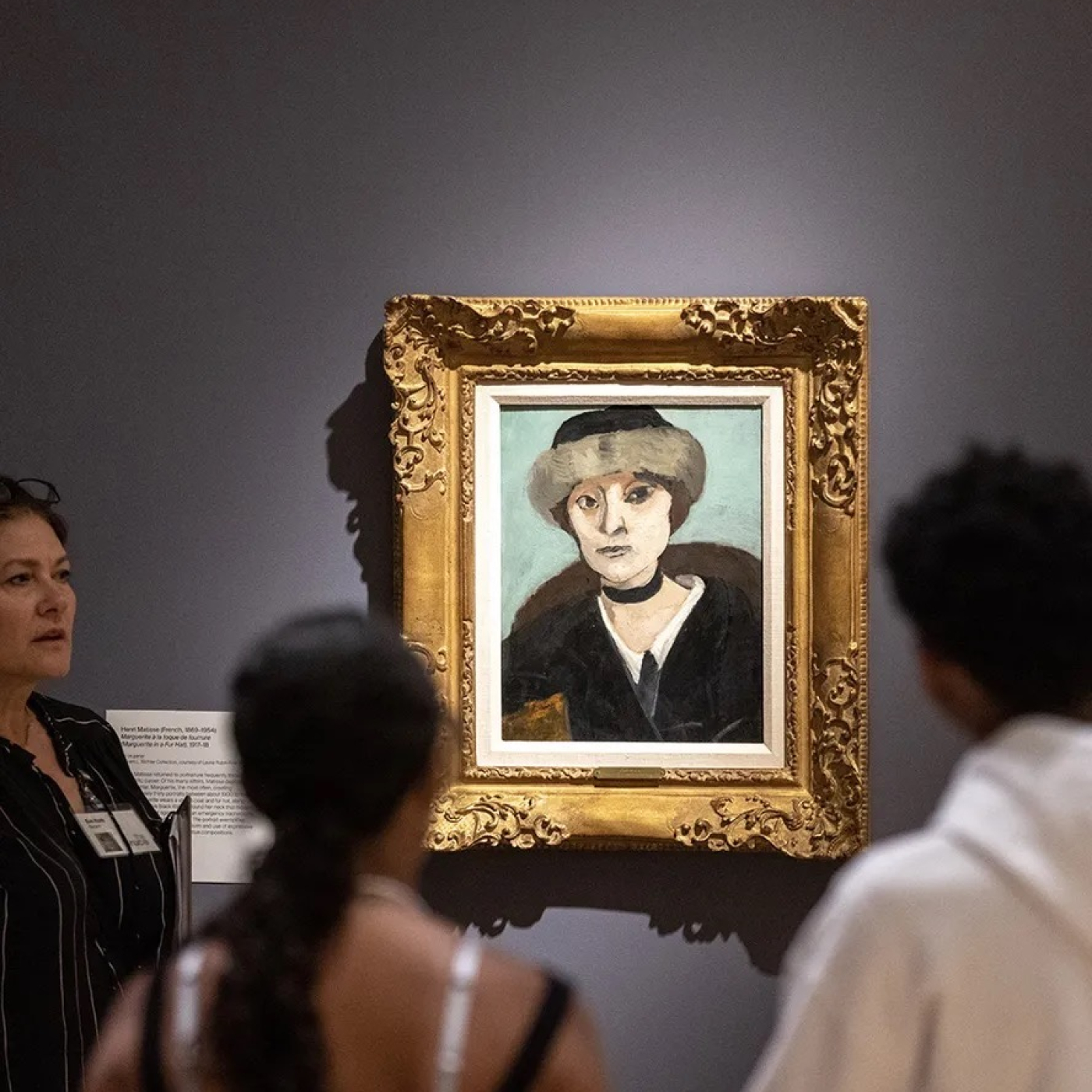 People in a museum looking at a portrait 