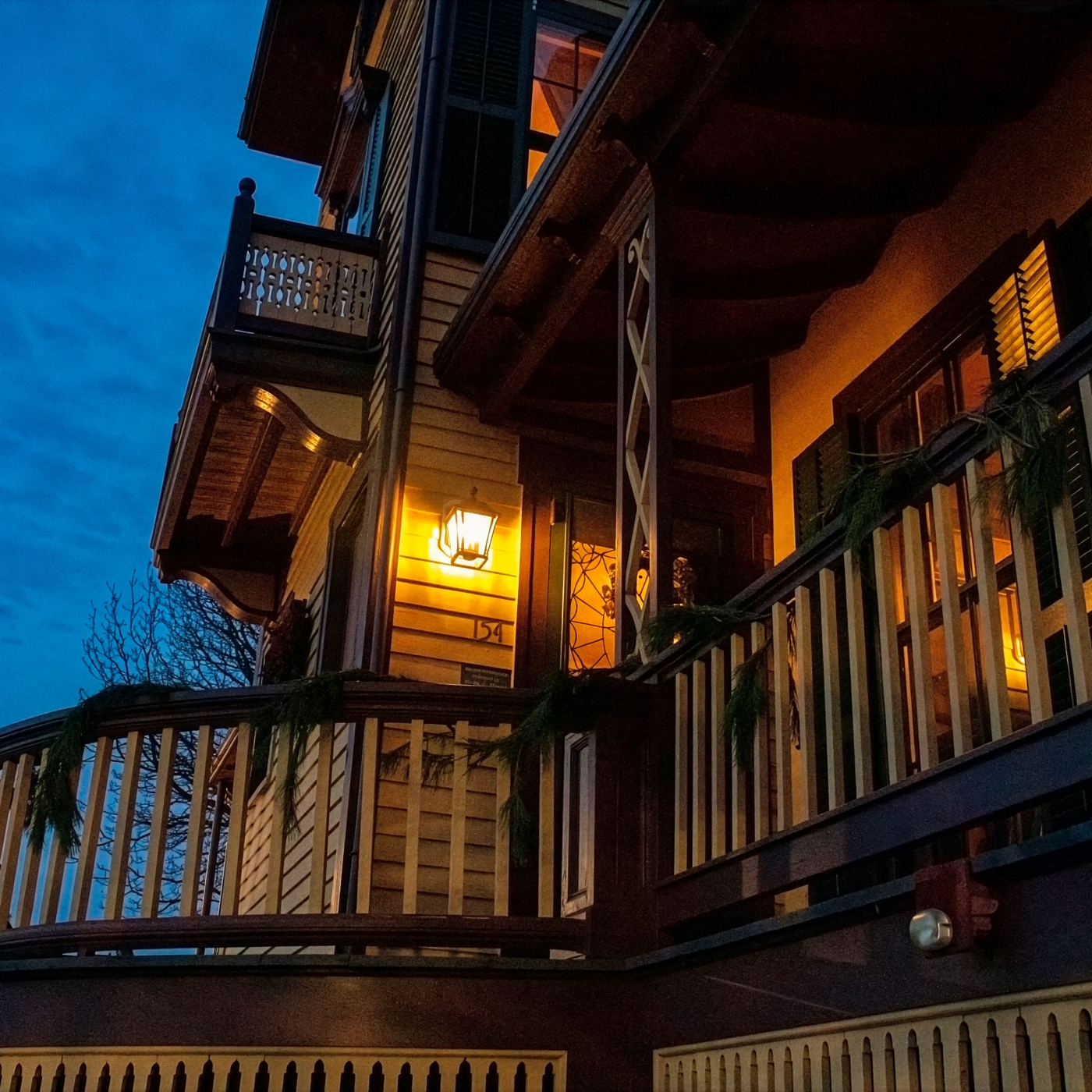 Victorian home at dusk glowing with warm lights, creating an eerie setting for a Haunted Harbor Tour. 