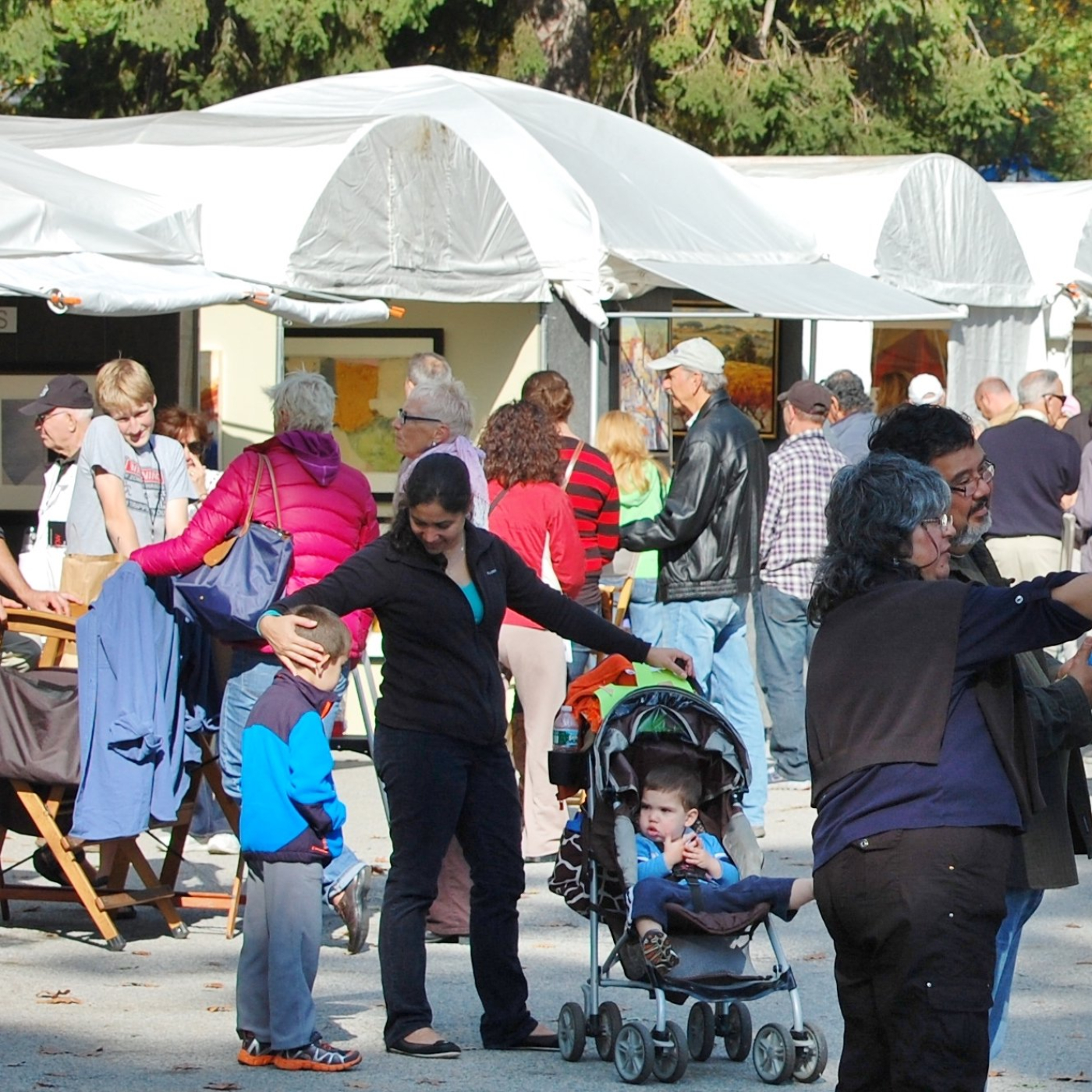 People milling about at an arts festival with tents in background.