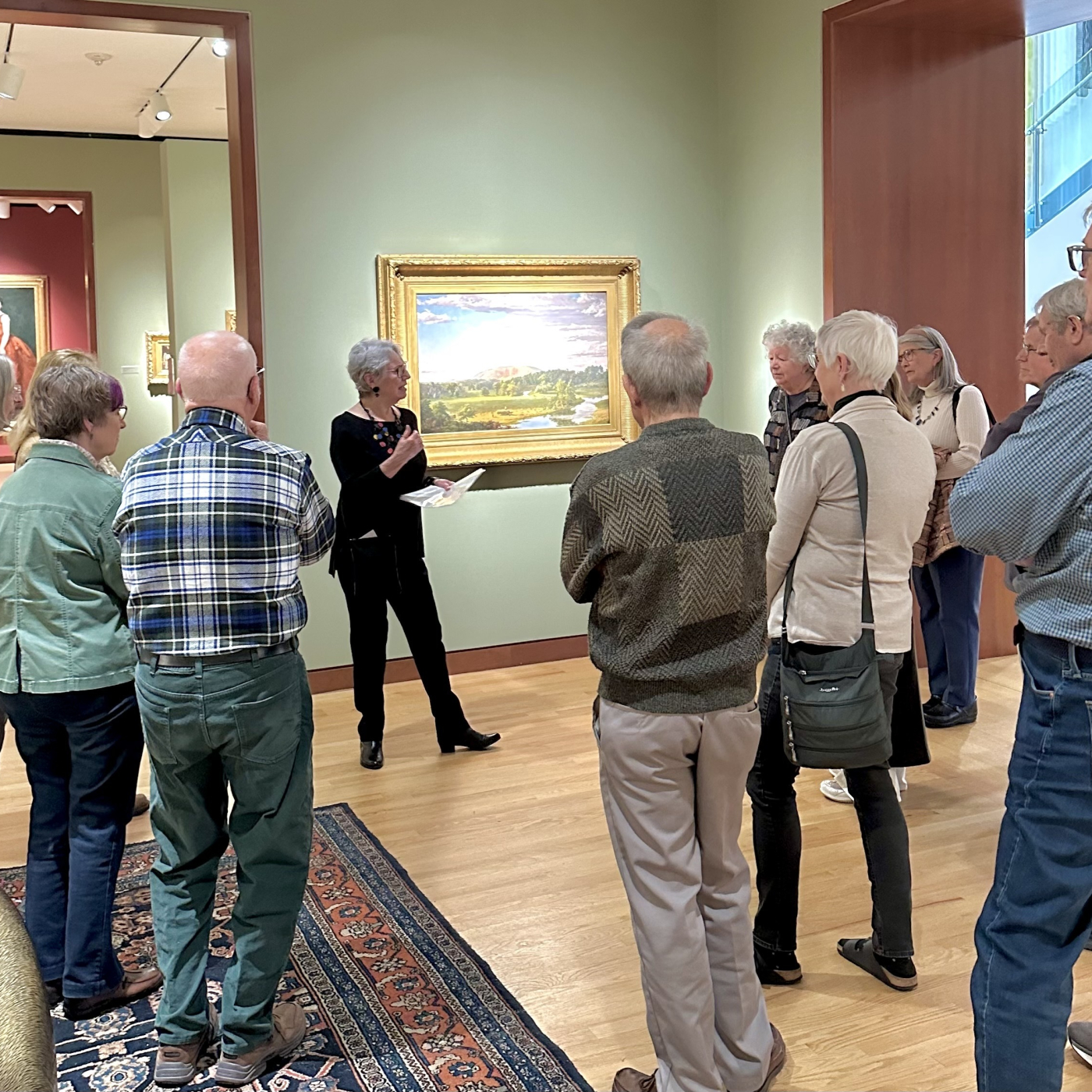 group of visitors in a Museum gallery looking at a landscape painting
