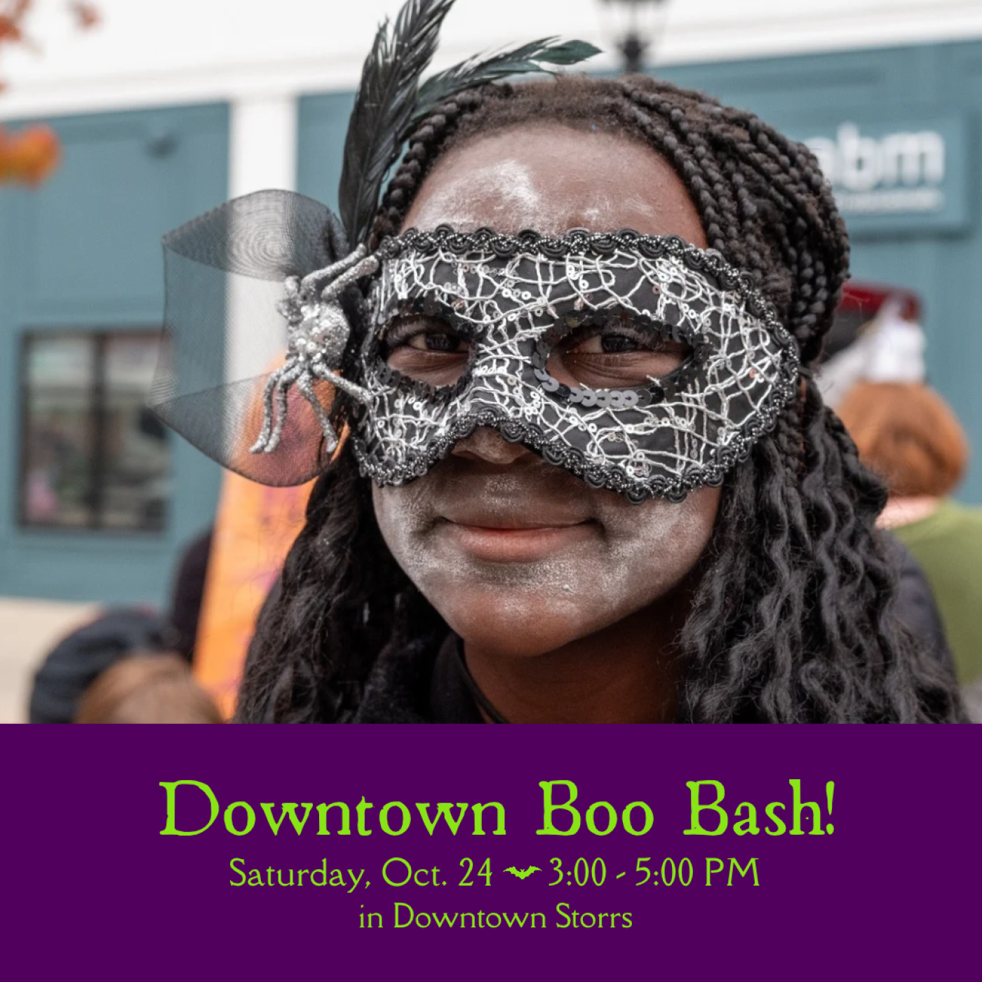 A teen wears a Halloween mask adorned with a glittering spider and black feathers