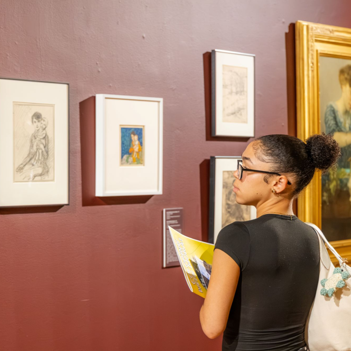 Photograph of student looking at framed artwork by F. Luis Mora