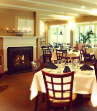 Cozy dining room with fireplace, set tables, and large windows
