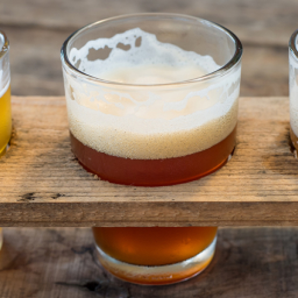 Three small glasses of craft beer on a wooden tasting flight board