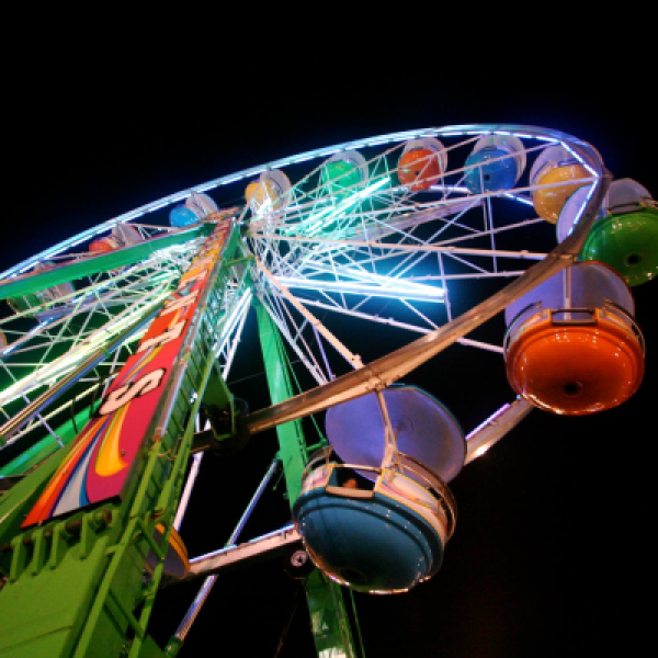 Colorful Ferris wheel lit up at night against black sky