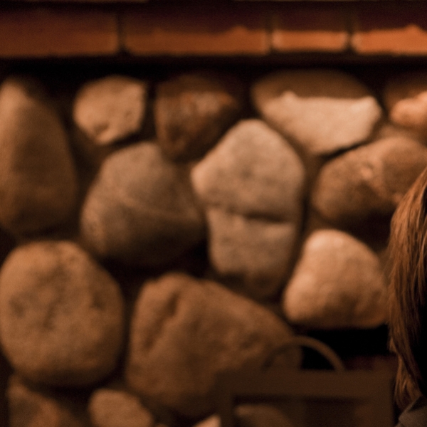 Couple dining near a stone fireplace with drinks and bread basket