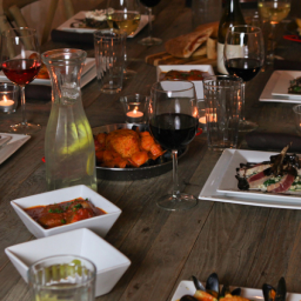 Rustic wooden table set with gourmet dishes, wine glasses, and lit candles