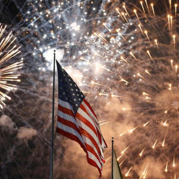 American flag with colorful fireworks exploding in night sky