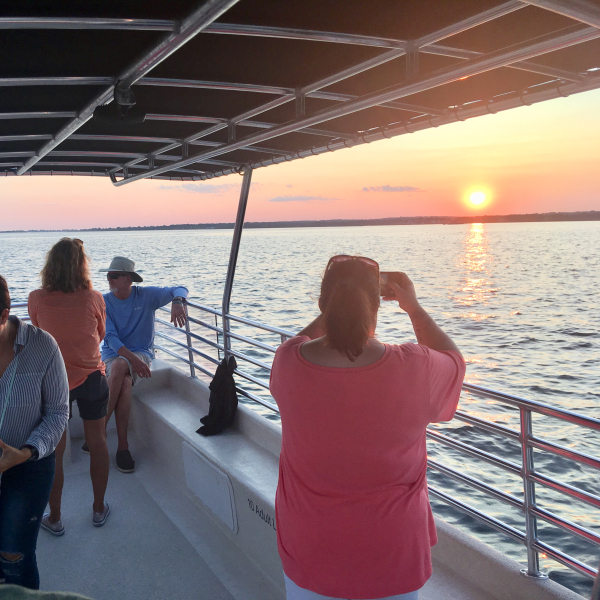 A group on a Sunset Harbor Cruise taking pictures of the sunset over the horizon