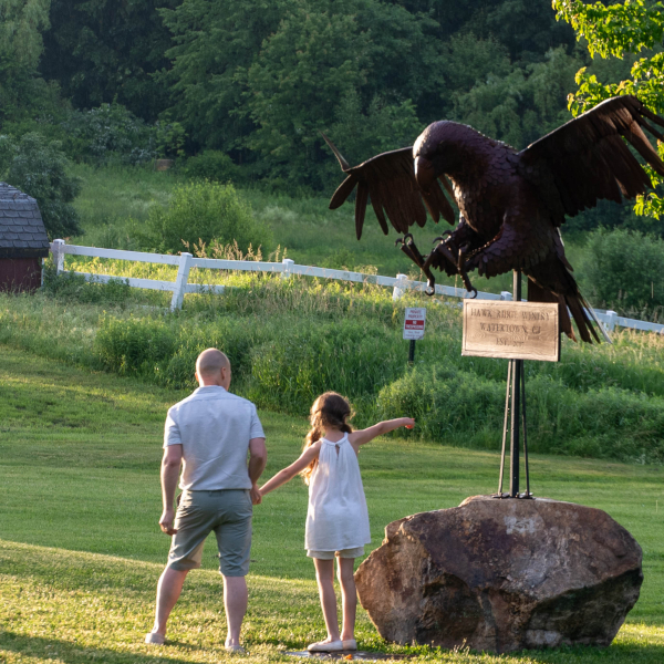 A father and daughter stand next to our Hawk Statue