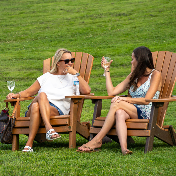 Two women sitting on the lawn with glasses of wine