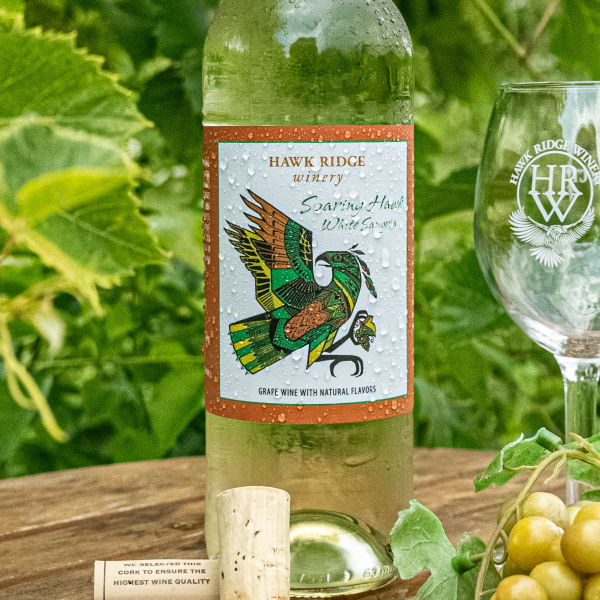 A chilled bottle of Soaring Hawk White Sangria with a glass in the vinyard