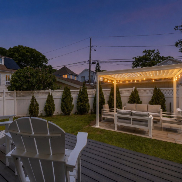 Outdoor living area at Walnut Beach Luxury House with a lit louvered pergola, bluestone patio, Trex deck, and lounge seating.