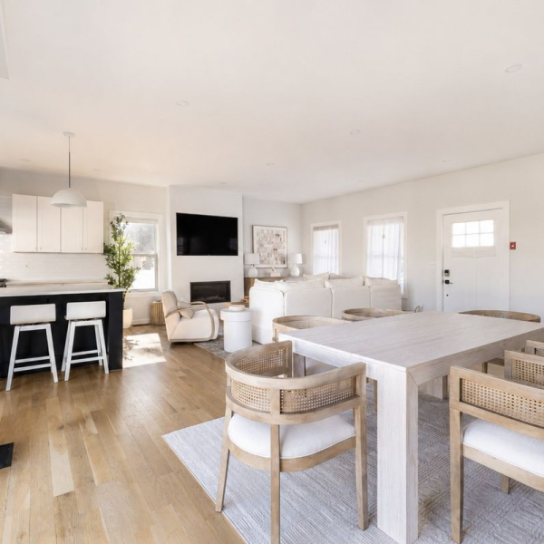 Bright open-plan living and dining area with 9-foot ceilings, wide-plank hardwood floors, gas fireplace, and chef's kitchen