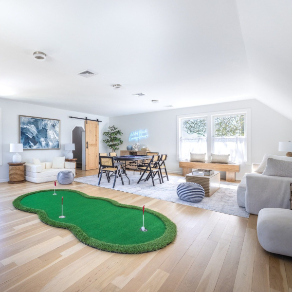 Spacious 600+ square-foot third-floor game lounge with putting green, card table, lounge seating, and second workspace 