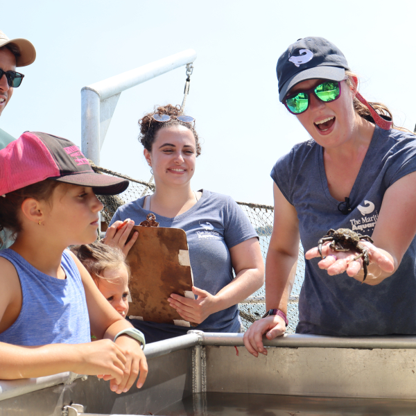 Aquarium educator showing a crab to visitors aboard the research vessell