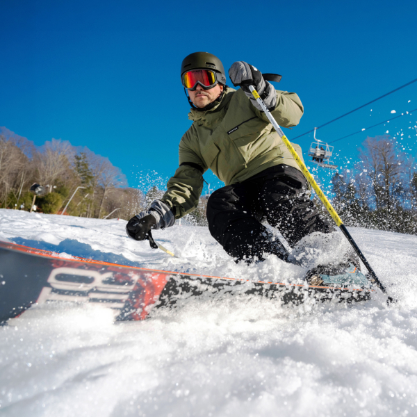 Skier carving on trail and creating snow spray