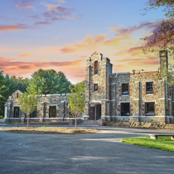 Stone building with arched entrance and trees at sunset