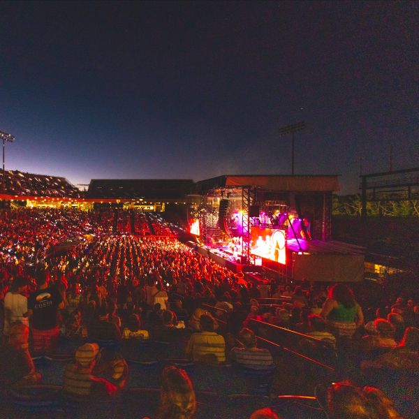 Large crowd watching a nighttime concert at an outdoor stadium