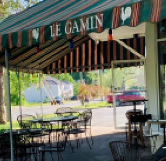Outdoor seating area under striped Le Gamin restaurant awning