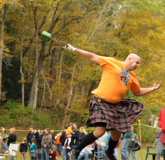 Man in kilt throwing hammer at Highland Games outdoors