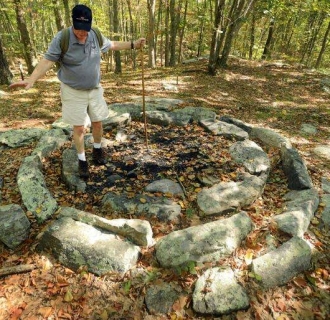 Man standing in center of circle of stones in a forest