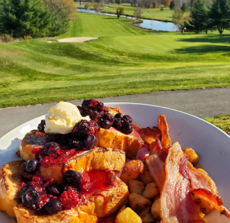 Un plato de tostadas francesas con beicon con vistas a un campo de golf en el 1741 Pub & Grill, Middlefield. 