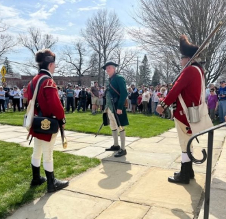 Two redcoats talking to a colonial patriot on the steps of the congregational church in Litchfield