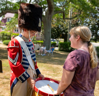 A revolutionary war reenactor and a museum visitor. 