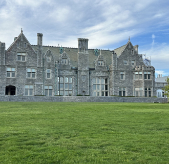 Branford House, a historic stone mansion overlooking a green lawn, featured on Thames River Heritage Park's Gilded Age tour.