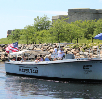 Hop On, Hop Off Harbor Cruise in the river with Fort Trumbull in the background.