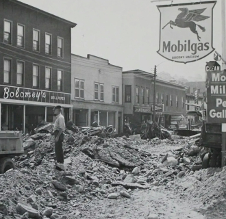 Historical photo of the town of winsted with rubble and deposits piled up in the streets following the flood of 1955.