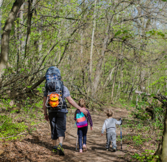 A family goes out for a hike on a sunny day.