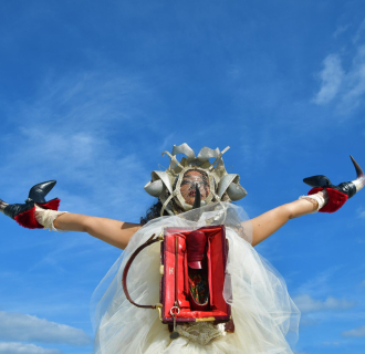 An image of a person wearing an elaborate outfit against a blue sky