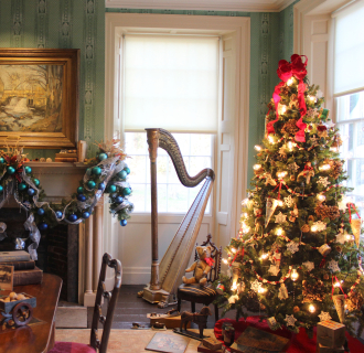 The historic parlor at the Florence Griswold Museum decorated for the holidays: a lit Christmas tree and decorated mantel