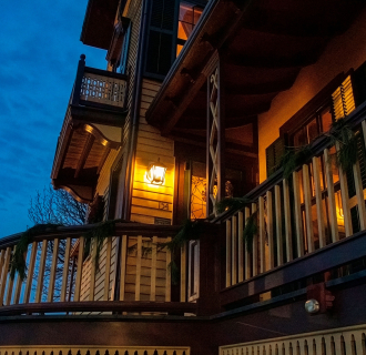 Victorian home at dusk glowing with warm lights, creating an eerie setting for a Haunted Harbor Tour. 